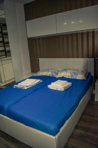 Una cama con sábanas azules y toallas blancas. en apartament valcea, en Râmnicu Vâlcea