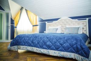 a blue bedroom with a large bed with a white headboard at Gosudar Hotel in Kropyvnytskyi