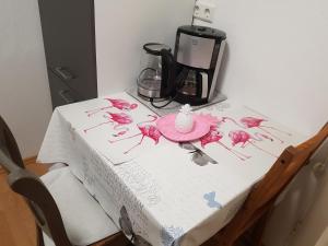 a table with a white table cloth with pink flowers on it at Ferienwohnung im Mühlbachtal in Miehlen