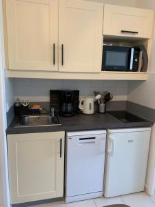 Una cocina con gabinetes blancos, un fregadero y un microondas. en Appartement agréable en bord de mer, en Villefranche-sur-Mer 7 fotos más