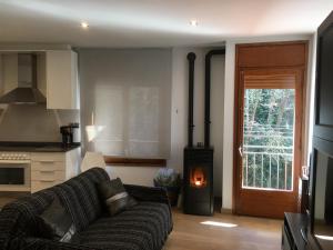 a living room with a couch and a wood stove at Precioso apartamento con vistas montaña y rio in Ribes de Freser