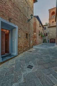 un callejón con un edificio de ladrillo y una puerta en La Rocca, en Gambassi Terme