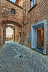 Une allée avec un bâtiment en briques avec une arche dans l'établissement La Rocca, à Gambassi Terme