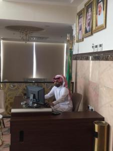 een man aan een bureau met een computer bij Kol Alayam Hotel in Mekka