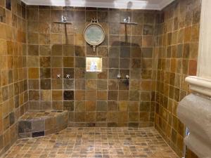 a bathroom with a tiled shower with a tub at La-Perna Guesthouse and Venue in Pretoria