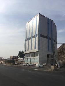 un gran edificio con coches estacionados frente a él en Kol Alayam Hotel, en La Meca