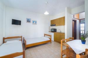 a room with two beds and a table and a kitchen at Kritikos Apartments in Pyrgadikia