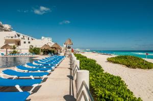 a row of lounge chairs on a beach next to the ocean at HotelZone L16 Beach Access in Cancún