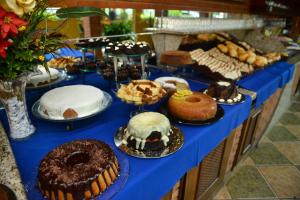 a blue table with different types of cakes and pastries at Hotel Porto dos Milagres in Aparecida