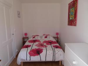 Un dormitorio con una cama con flores rojas. en Gîte en Brenne Les Chênes, en Mérigny