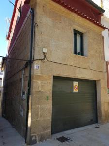 un edificio de ladrillo con una puerta de garaje y una ventana en Adro Redondela, en Redondela