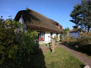 ein Haus mit einem Strohdach und einem Garten in der Unterkunft Landhaus Darss in Wieck