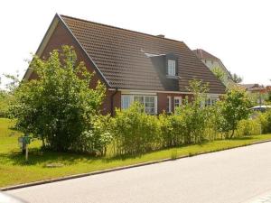 a brown house with a black roof and some bushes at Ruegen_Fewo 230 in Thiessow