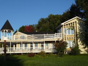 a large white house with a large deck at Dans Les Bras de Memphré in Magog-Orford