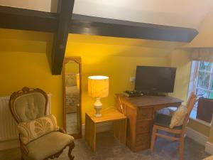 a living room with a tv and a chair and a desk at The Bell at Old Sodbury in Chipping Sodbury