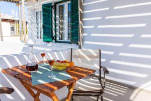 a wooden table with two glasses of wine and fruit at Naxian City Rooms in Naxos Chora