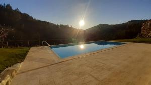 a swimming pool with the sun in the background at Quinta do Moinho in Castelo de Paiva