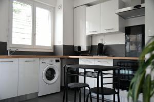 una cucina con armadi bianchi e una lavatrice/asciugatrice di Appartement Tropical et JACUZZI Balnéothérapie Draveil a Draveil