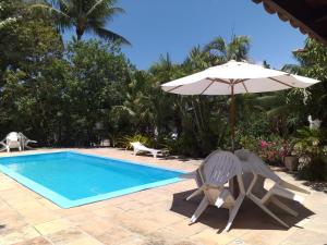 a pair of chairs and an umbrella next to a swimming pool at Residencial Coroa Vermelha in Santa Cruz Cabrália