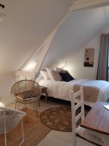 a bedroom with a bed and a chair and a table at Chambres D´Hôtes Herbes Folles in Steenwerck