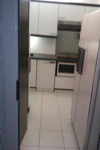 eine Küche mit weißen Schränken und weißen Fliesenböden in der Unterkunft T2 FRONT DE MER SUR LA PLAGE (ACCES PRIVE DIRECT PLAGE) VUE MER ET MONTAGNE in Argelès-sur-Mer