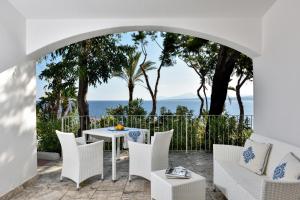 eine Terrasse mit einem Tisch, Stühlen und Meerblick in der Unterkunft Arbatax Park Resort - Cottage in Àrbatax