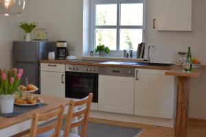 eine Küche mit weißen Schränken, einem Tisch und einem Waschbecken in der Unterkunft Ferienwohnung am Sattelhof in Türnitz