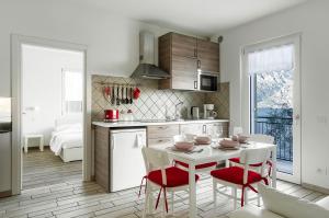 cocina con mesa blanca y sillas rojas en Casa Antonio en Malcesine