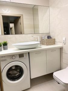 a bathroom with a washing machine and a sink at Apartament Sucharskiego in Toruń