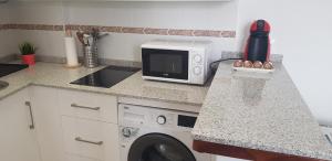 een keuken met een magnetron en een wasmachine bij Apartamento Conil Playa & Centro, perfecto descanso, con Aire Acond y WIFI in Conil de la Frontera