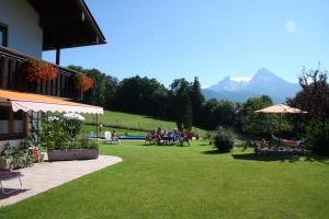 a group of people sitting on a lawn with mountains in the background at Pension Elvira in Bischofswiesen