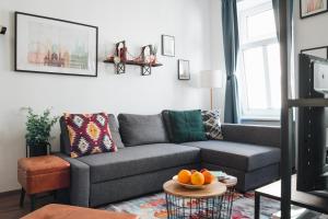 a living room with a gray couch and oranges on a table at Design Apartment with King Size Bed - Six Minutes to Opera in Vienna