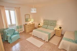 a bedroom with a bed and a chair and a mirror at Le Case di Felicita in Santa Teresa Gallura