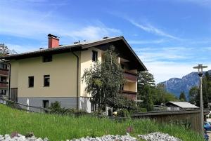 dom na wzgórzu z górami w tle w obiekcie Ferienwohnung mit Seeblick, Unterach am Attersse w mieście Unterach am Attersee