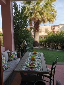 een tafel en stoelen op een patio met een palmboom bij Villetta con giardino in Residence IN CENTRO in Villasimius