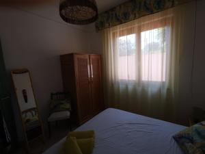 een slaapkamer met een bed, een raam en een spiegel bij Villetta con giardino in Residence IN CENTRO in Villasimius