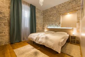 sypialnia z łóżkiem i kamienną ścianą w obiekcie Tifani Luxury Rooms w Splicie