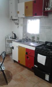 a kitchen with a stove and a sink and a window at La Casita in Neuquén