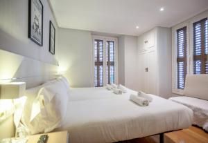 two beds in a bedroom with white walls and windows at Pension Larrea in San Sebastián