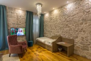 sala de estar con pared de piedra, sofá y silla en Tifani Luxury Rooms 2, en Split