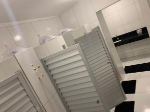 a bathroom with white cabinets and a sliding door at Manhatã Hostel in Salvador +79 photos