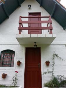uma casa branca com uma porta vermelha e uma varanda em marcita chalé em Monte Verde