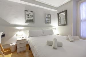 a white bedroom with a large white bed and a mirror at Pension Larrea in San Sebastián