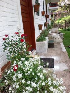 un jardín con flores rojas y blancas junto a una puerta en marcita chalé, en Monte Verde