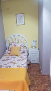 um pequeno quarto com uma cama e uma mesa de cabeceira em LAS MARGARITAS em Gijón