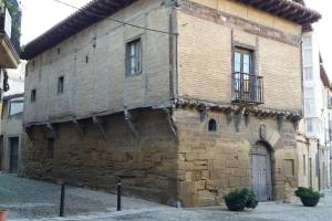 un antiguo edificio de ladrillo con puerta y balcón en BONITO ALOJAMIENTO EN BRIONES, en Briones