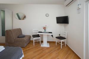 a room with a table and a chair and a tv at Guest House Kušeta in Split