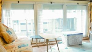 a living room with a couch and a table and windows at Appartement Cosy sur Port de Plaisance in Capbreton