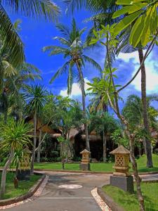 a driveway with palm trees in front of a house at Salim Beach Resort in Gili Air
