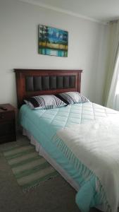 Un dormitorio con una cama grande con cabecero de madera. en La Serena hermosa, en La Serena